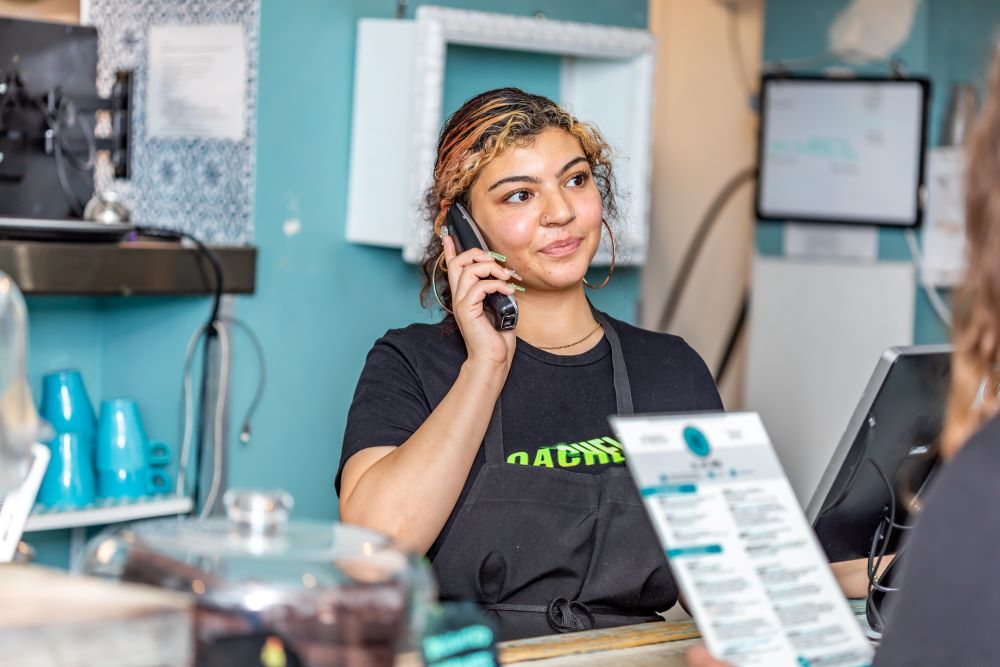 Restaurant employee answering the phone at the counter