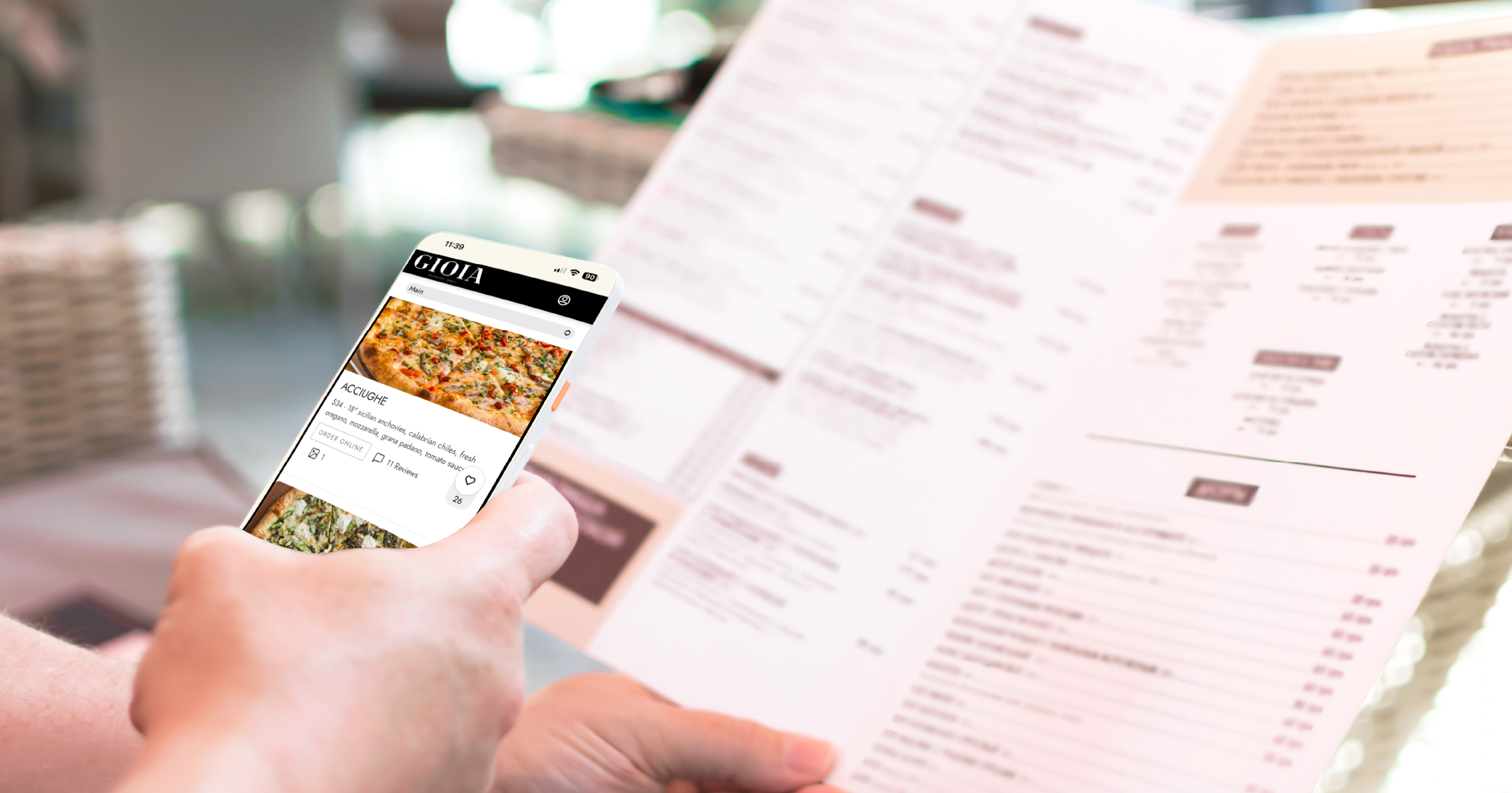 Phone showing an online ordering app held up next to a printed menu