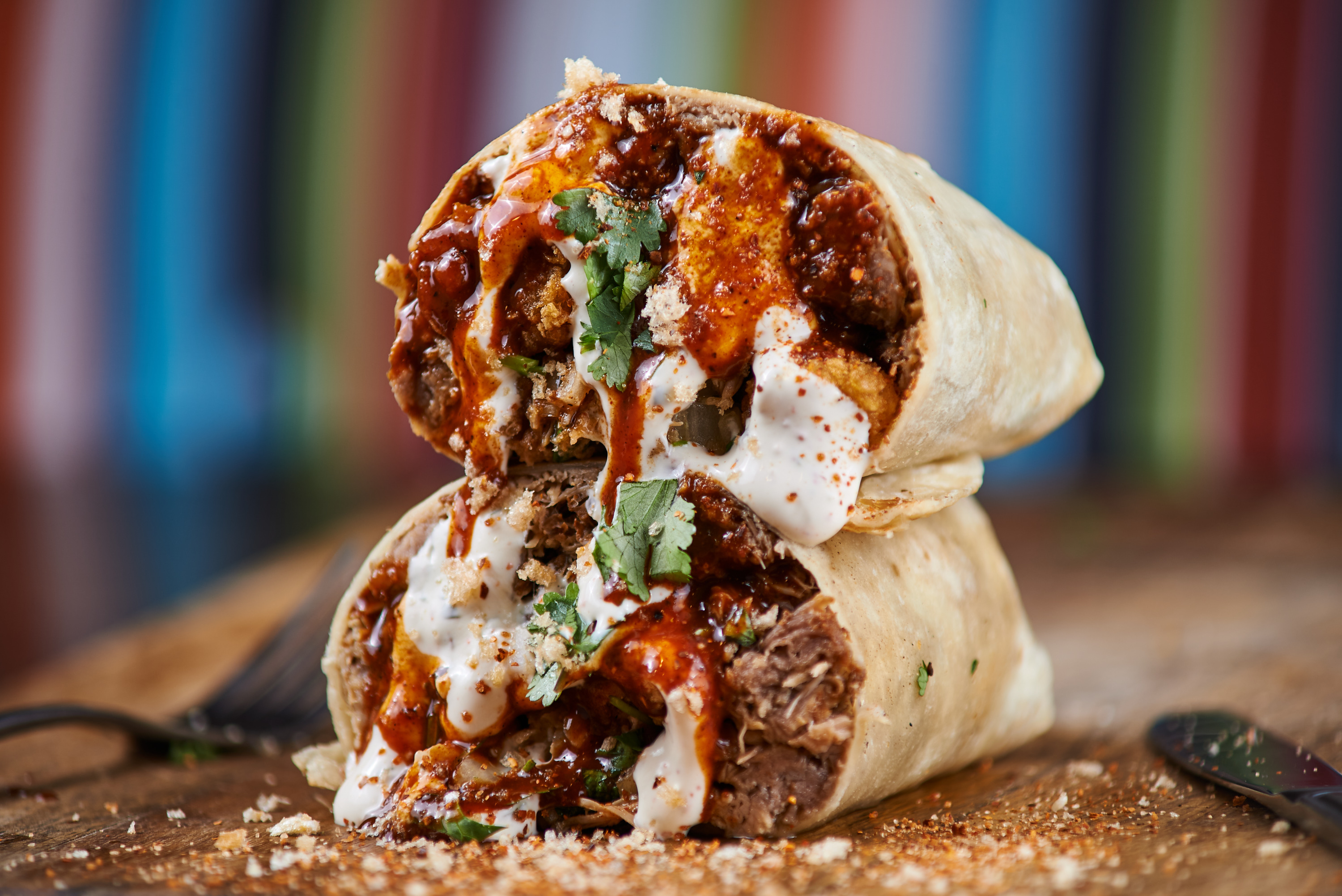 Burrito cut in half revealing meat, sauce, and cilantro filling