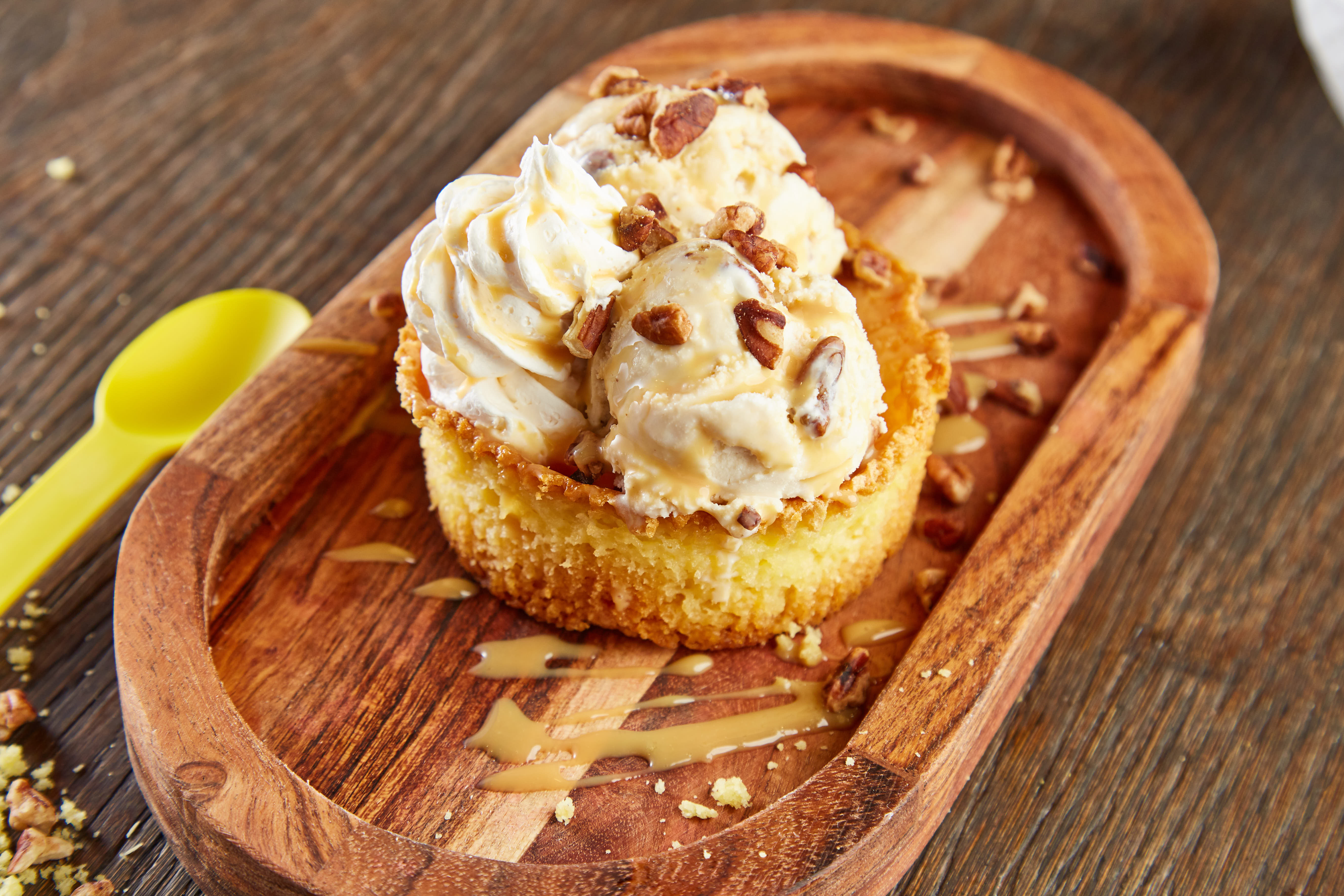 Ice cream scoops with caramel and pecans atop a cake base