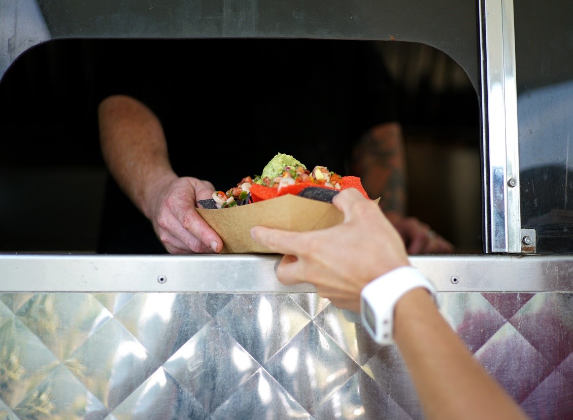 Food truck window handoff of a wrapped taco to a customer