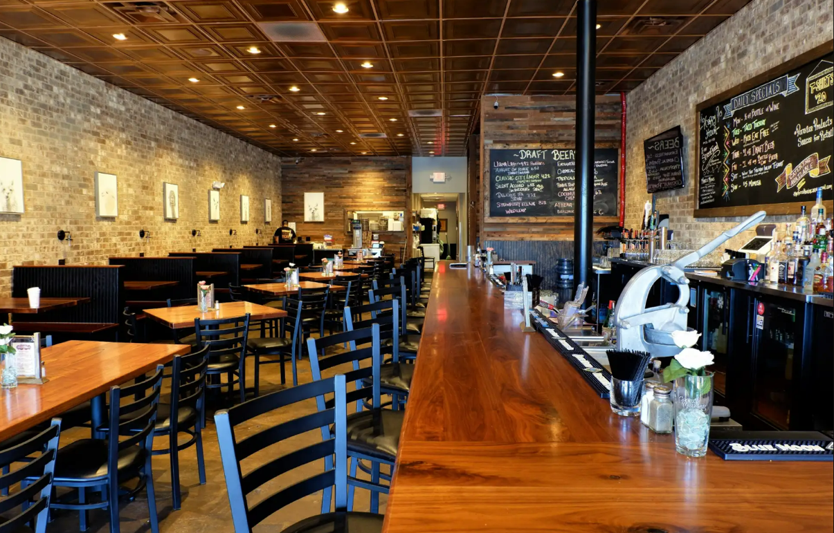 Restaurant interior with a wood bar and exposed brick walls