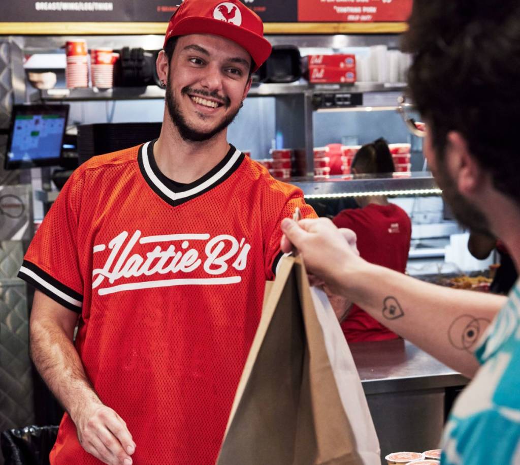 Hattie B’s employee handing a takeout order to a customer