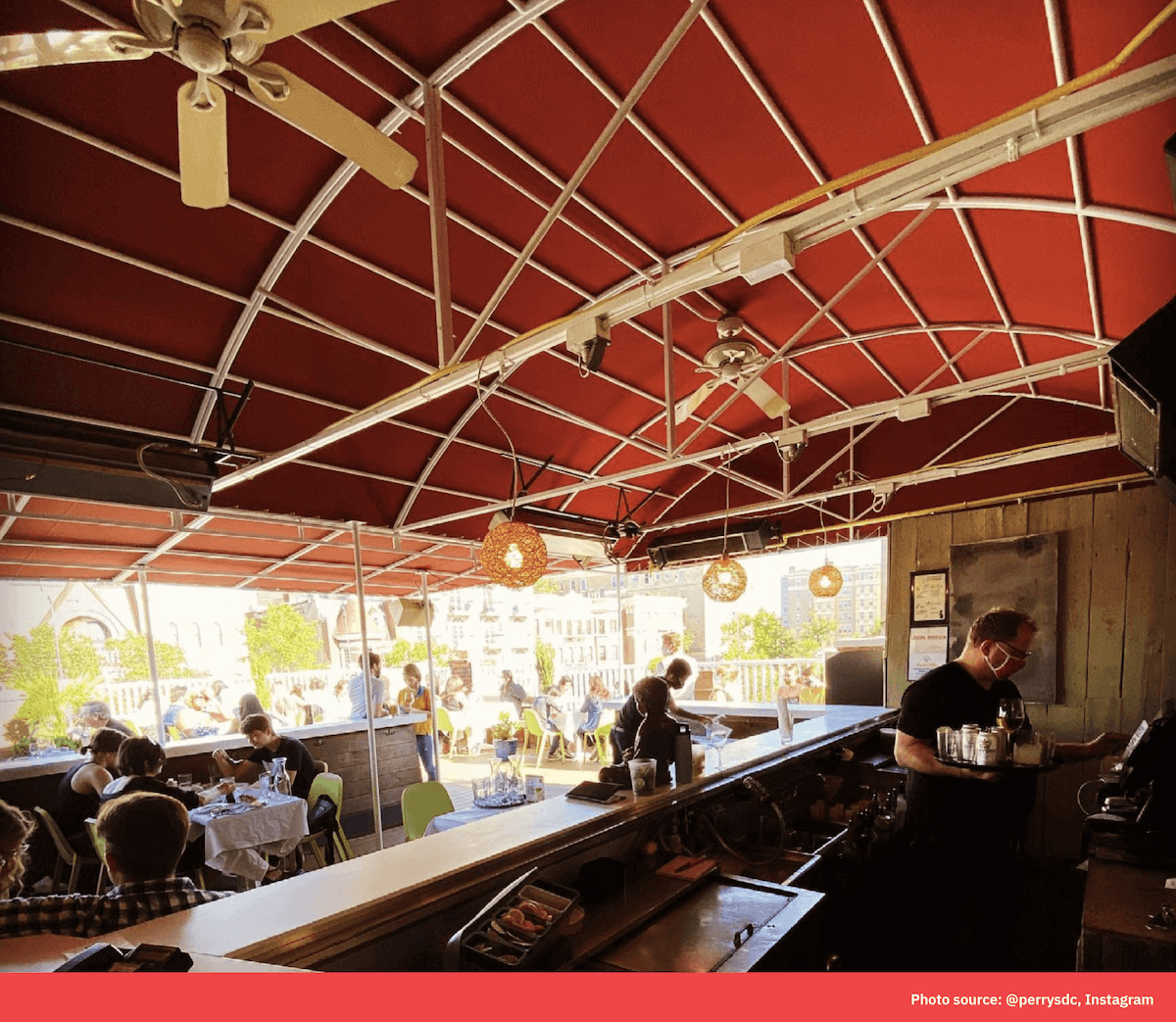A covered outdoor bar area with a red awning where staff prepare drinks and food for guests