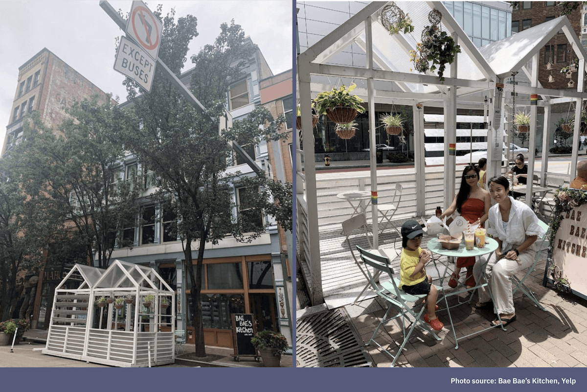 A small greenhouse-style outdoor dining structure on a city sidewalk, and a family seated at an outdoor cafe table