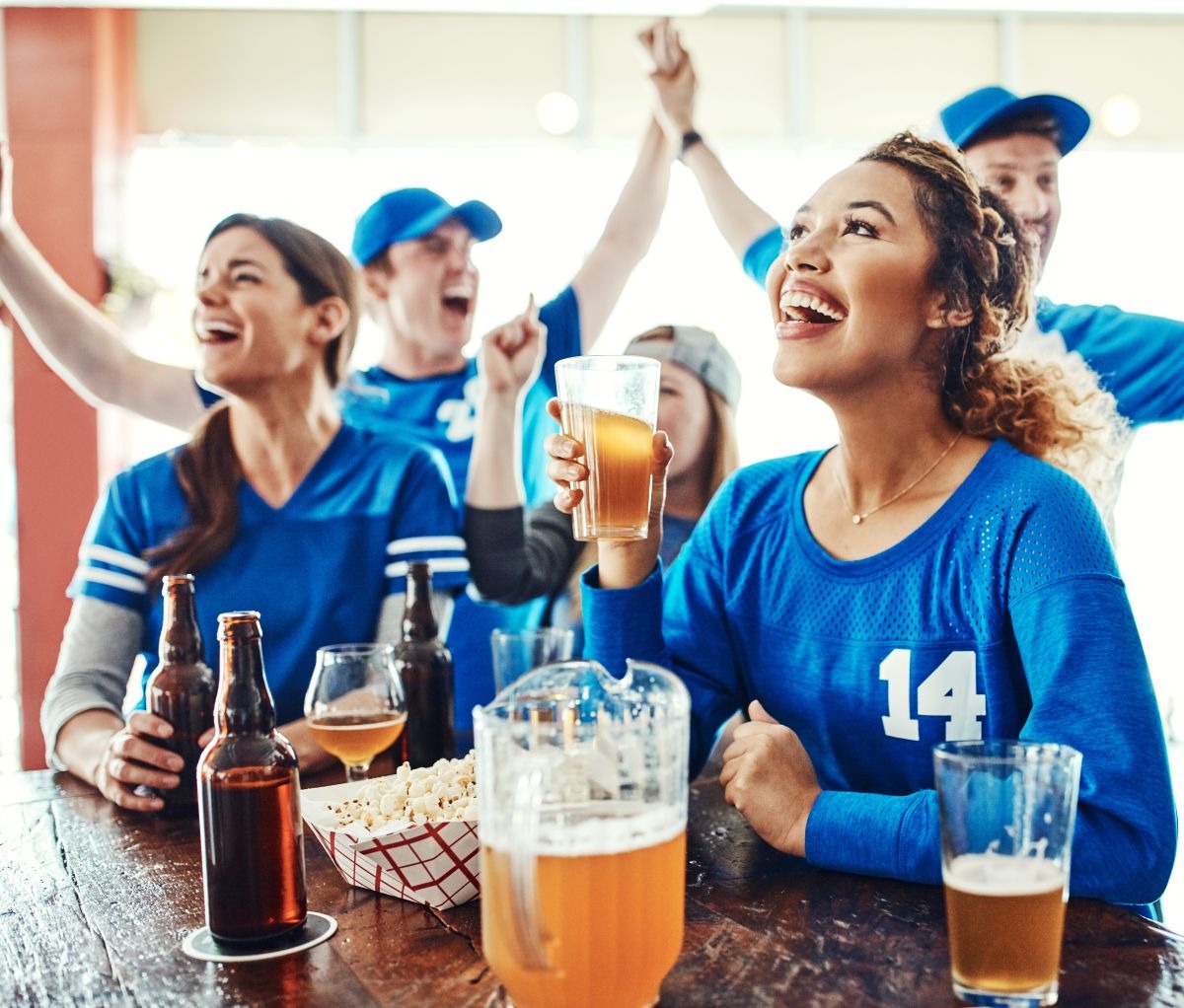 Group of friends cheering with beer at a game-day watch party