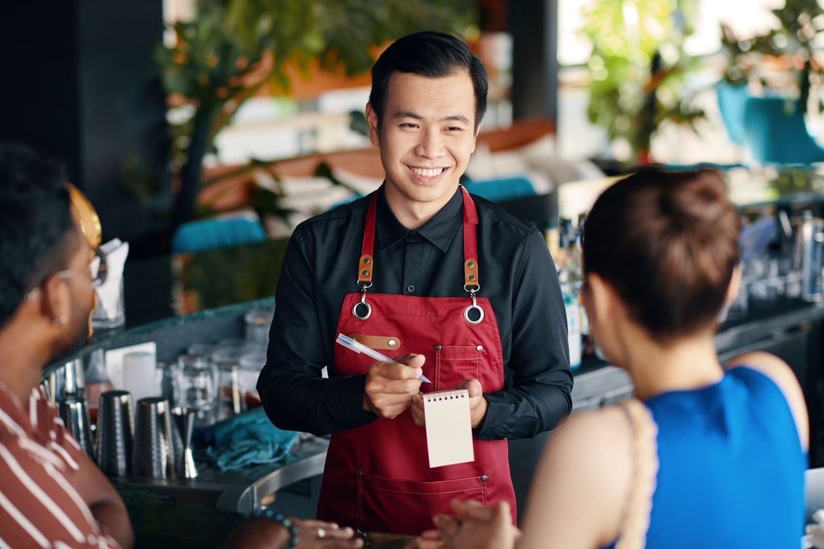 Smiling waiter taking an order from restaurant guests