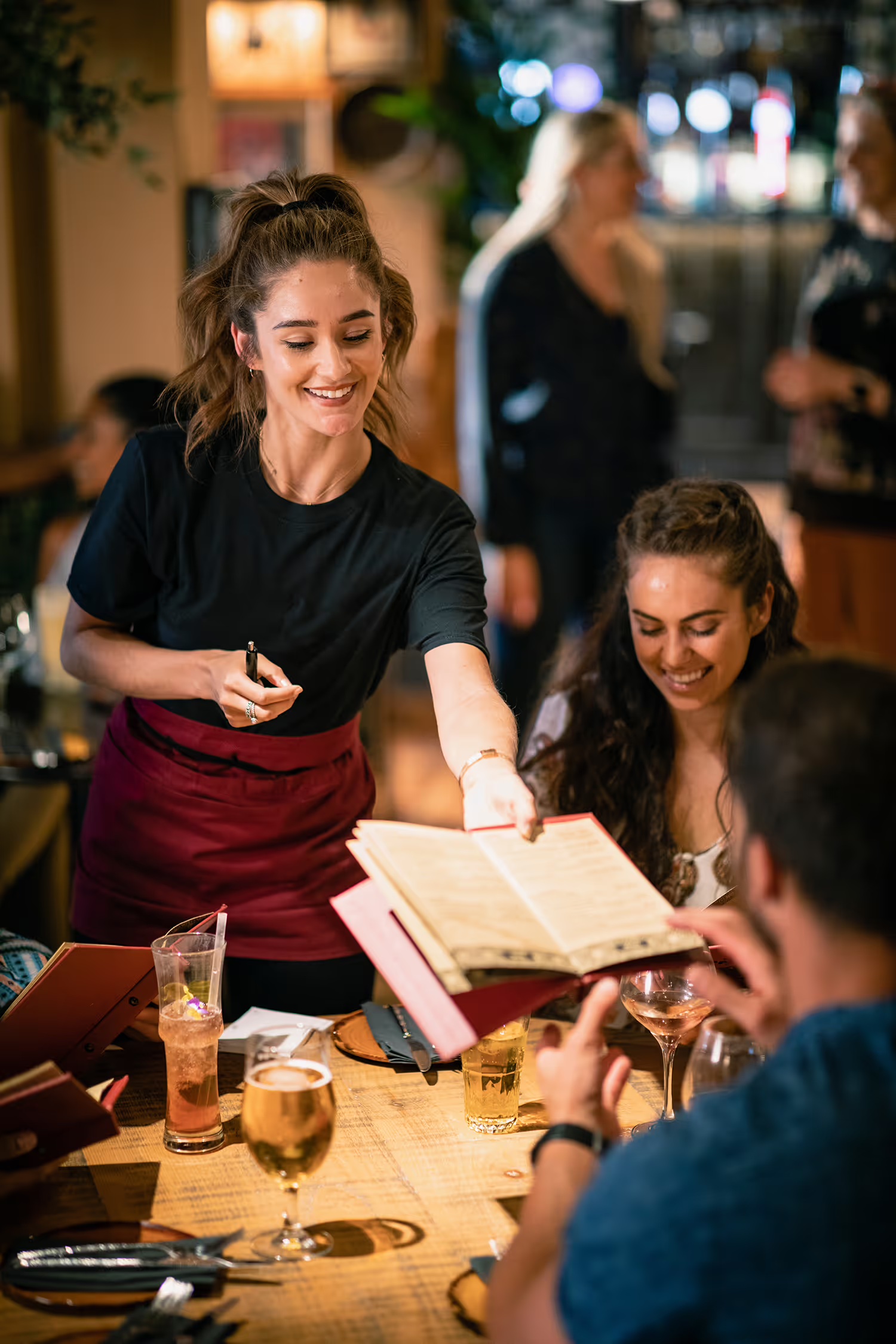 A server presenting a physical menu to guests at a restaurant table