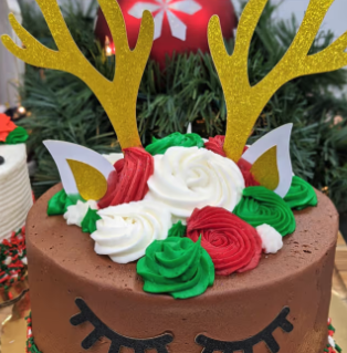 A chocolate cake decorated with gold reindeer antlers and holiday frosting
