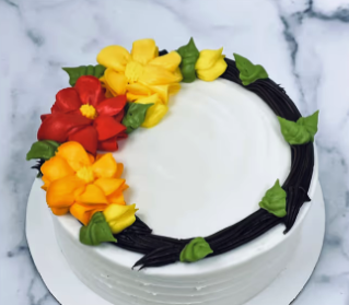 A white cake decorated with red, orange, and yellow flowers