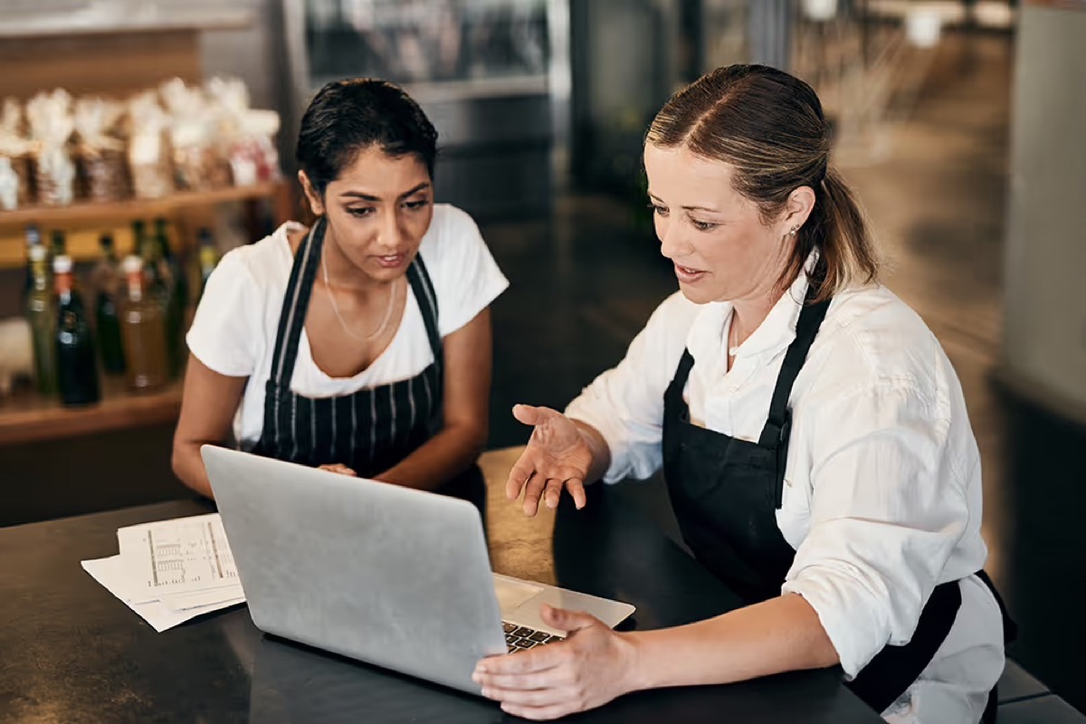 Two restaurant employees reviewing figures together on a laptop