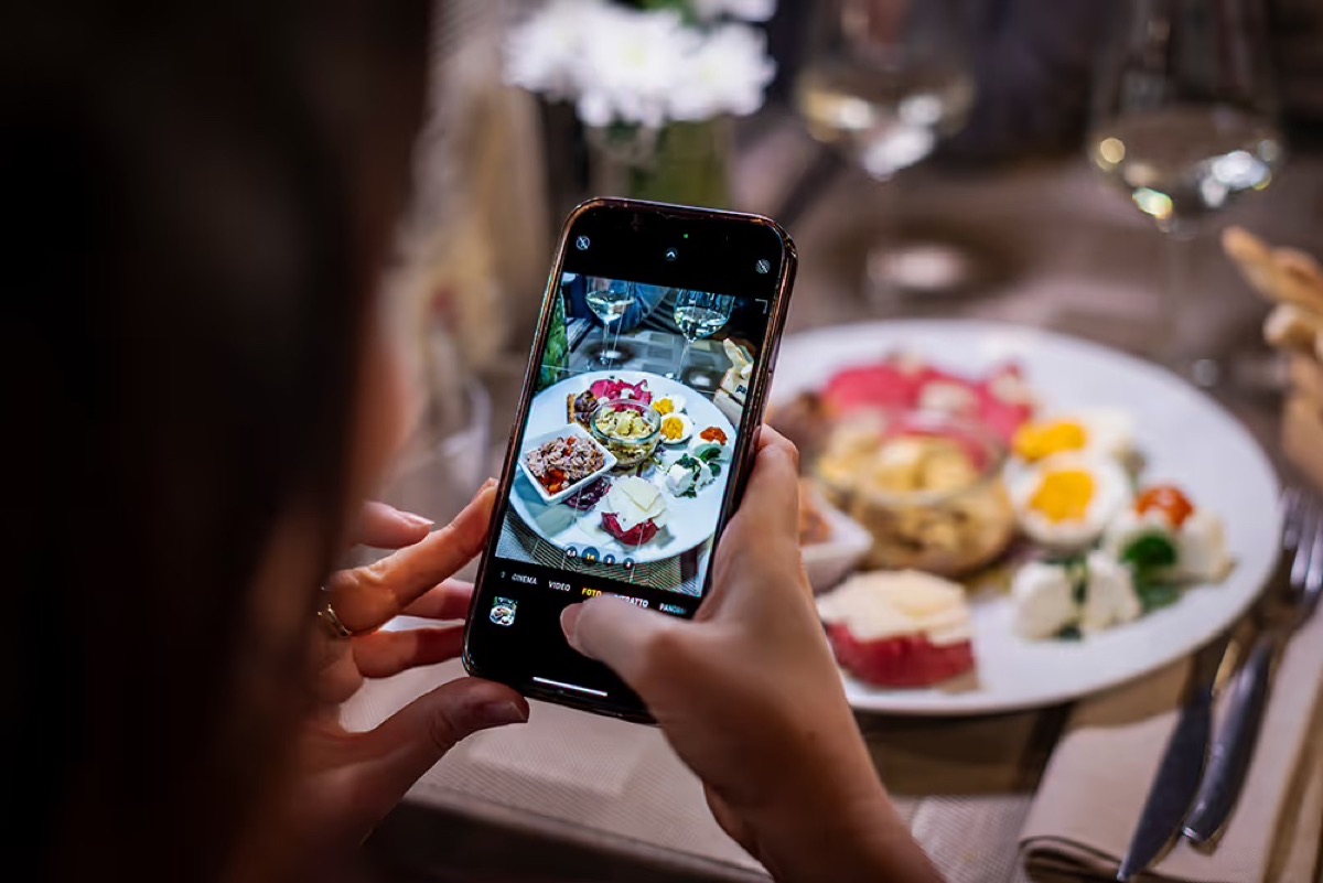 A restaurant guest photographing a plated dish with a smartphone