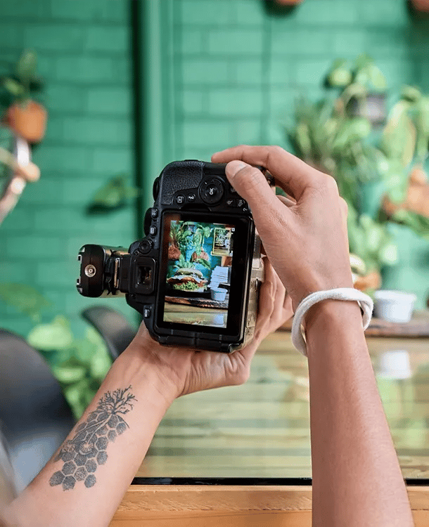 Photographer reviewing a food photo on a camera during a restaurant photoshoot